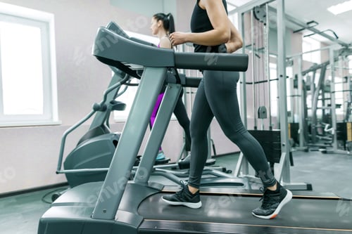 Preview: Two young fitness healthy women on treadmill in the sport modern gym.