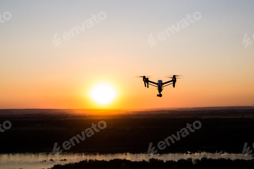 Preview: silhouette of drone, quadrocopter with photo camera flying in the sky