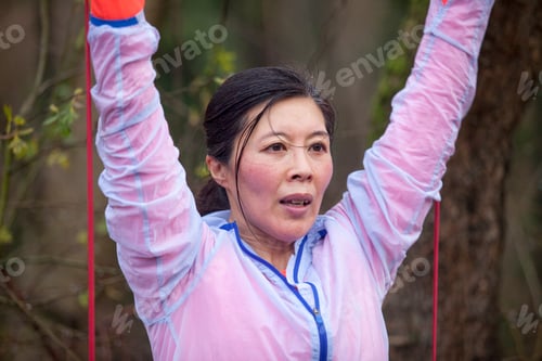 Preview: A focused woman exercises outdoors with resistance bands.