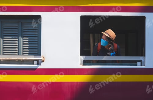 Preview: Traveler woman wears protective mask looking sideway from window of the old train at railway station