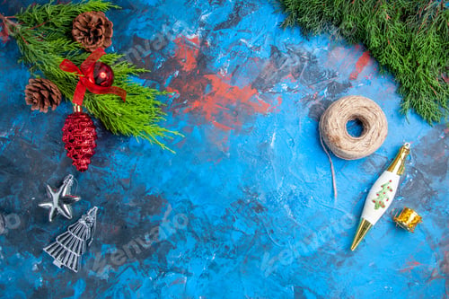 Preview: top view pine tree branches with pinecones hanging ornaments straw thread on blue-red background