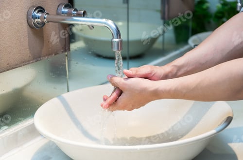 Preview: Hand washing with Chrome faucet over the washbasin in modern bathroom