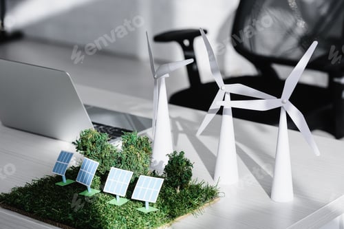 Preview: chair near table with laptop, trees, windmills, solar panels models on grass in office