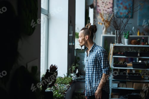 Preview: Handsome young man looking out the window at home