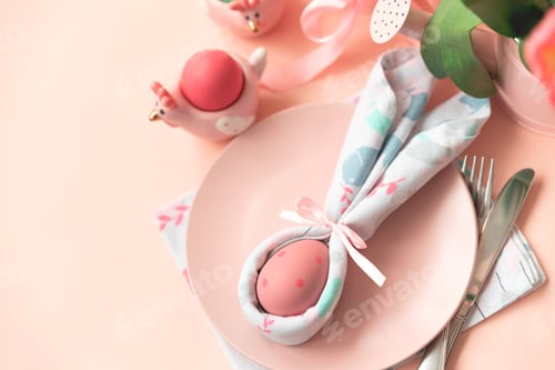 Preview: Festive Easter table setting with napkin Easter Bunny on pink table. Easter celebration concept.