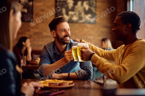Preview: Happy male friends toasting while drinking beer in a pub.