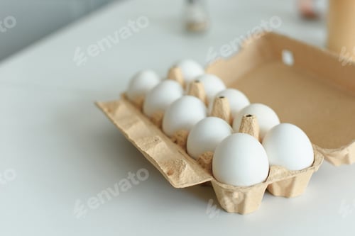 Preview: close up view of raw chicken eggs in box on tabletop in kitchen