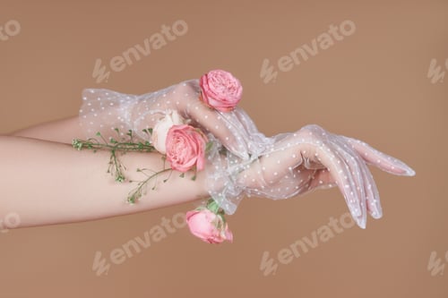 Preview: Hands wearing gloves hold pink flowers against a neutral background
