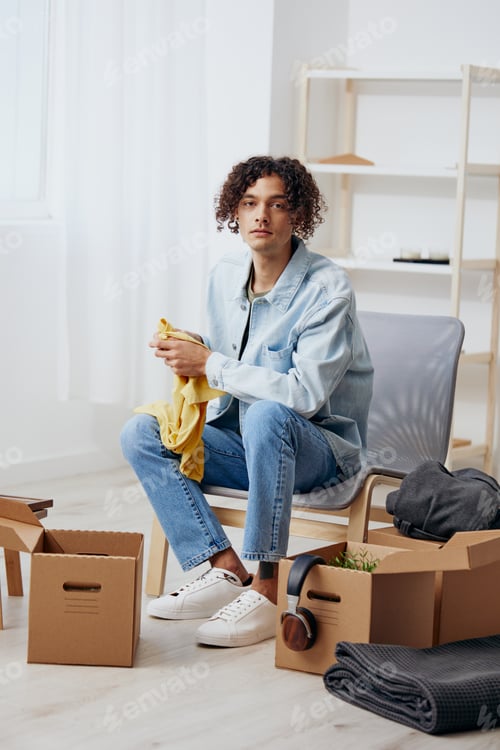 Preview: handsome guy sitting on a chair with boxes interior moving Lifestyle