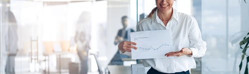 Preview: Positive mature businesswoman showing her new plans with graph in modern office