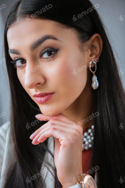 Vista previa: retrato de hermosa chica morena de pie con la mano en la barbilla y mirando a la cámara