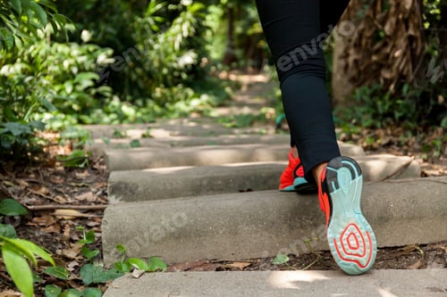Preview: Young athletic woman running on forest trail