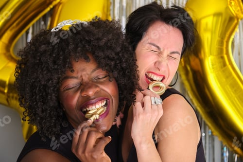 Preview: Two multiracial women in a 40 birthday party biting 40 birthday golden candles.
