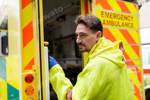 Preview: Paramedic standing near blurred ambulance car with open door outdoors