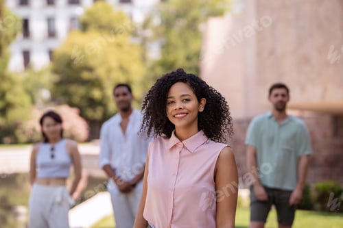 Preview: Young woman smiling with friends in background in the city