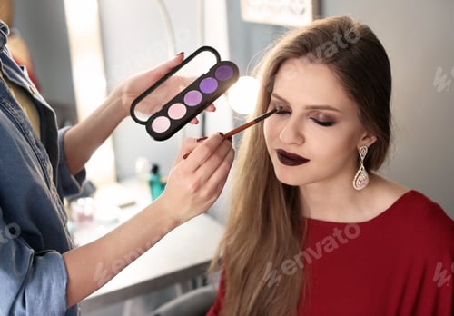 Preview: Professional makeup artist working with beautiful young woman in studio