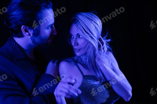 Preview: Young man touching blonde girlfriend with blue lighting isolated on black