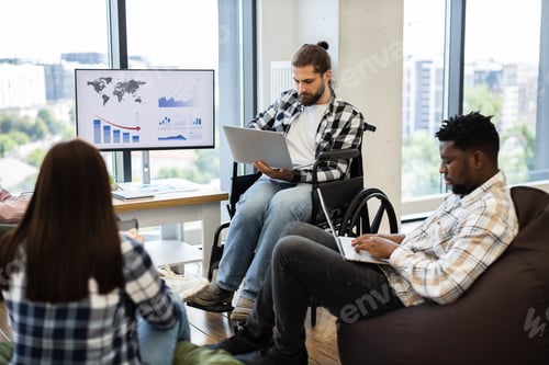 Preview: Two diverse men working on laptops in modern office environment