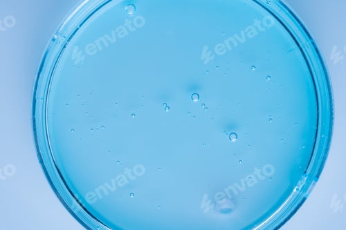 Preview: blue cosmetic product serum gel in petri dish. Liquid texture with bubbles on blue background.