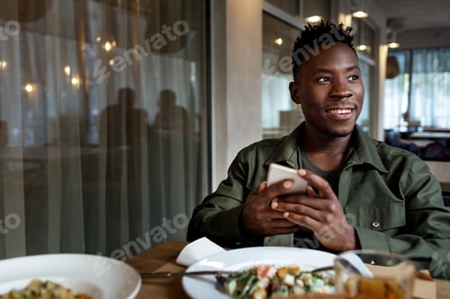 Preview: young african american man using laptop in cafe
