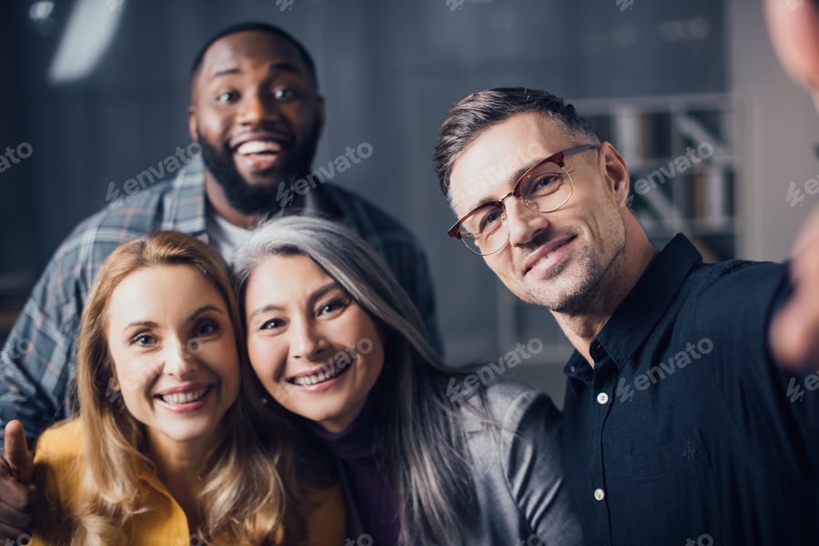 Cover for selective focus of smiling multicultural colleagues looking at camera and taking selfie