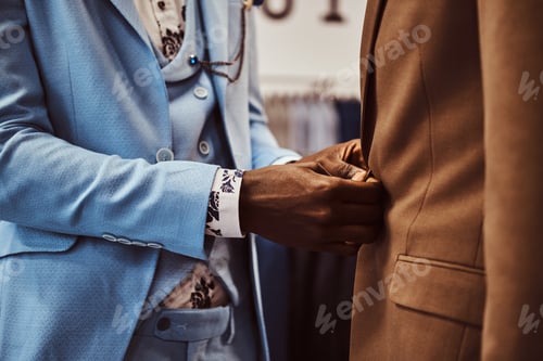 Preview: Elegantly dressed African-American man working at classic menswear store.