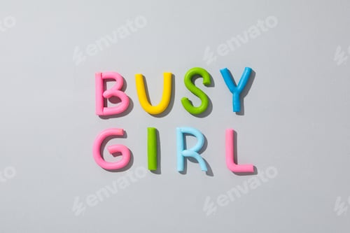 Preview: The word "busy girl" from colored plasticine on a gray background.