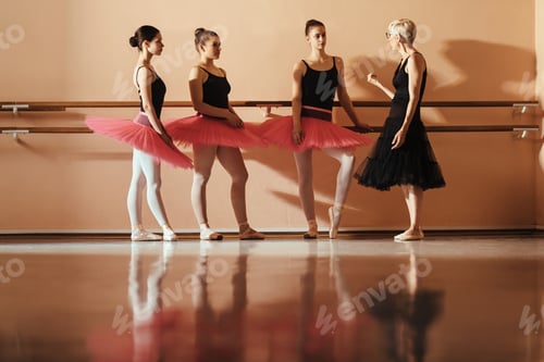 Preview: Mature ballet teacher communicating with teenage ballerinas at dance school.