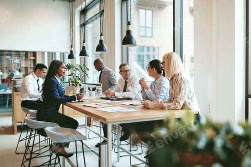 Preview: Diverse businesspeople smiling and talking together at an office table