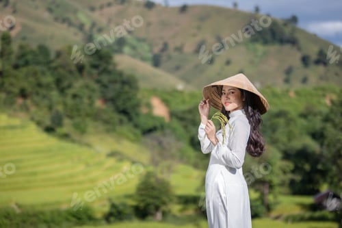 Preview: Vietnam girl in traditional white dress holding ears of rice and looking at camera.