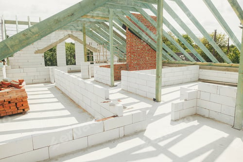 Preview: Unfinished roof trusses, view in attic with rafters, beams, windows and chimney. Wooden roof framing