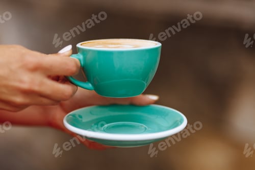 Preview: Close up of woman's hands holding light blue cup of coffee