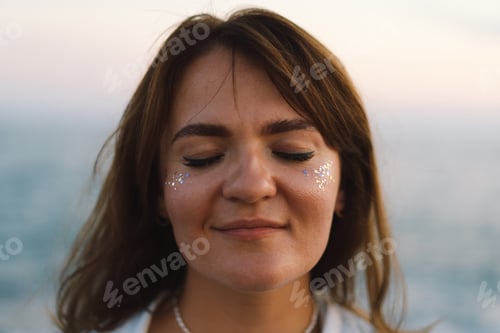 Preview: Portrait of a happy young girl with closed eyes on a background of beautiful sea.