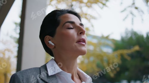 Preview: Smiling woman speaking earpods on go closeup. Successful freelancer walk street