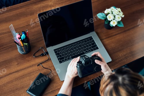 Preview: Female photographer working on photos on laptop and camera. Woman editing retouching browsing photos