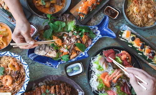 Preview: hands with chopsticks eating thai food close up, salads and wok, asian food, top view.