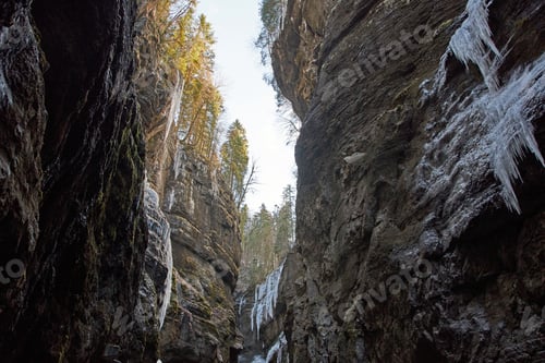 Preview: Low angle view of tall rocky gorge with icicles hanging from walls.