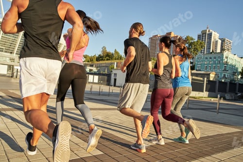 Preview: Rear view of young team running along paved pedestrian area