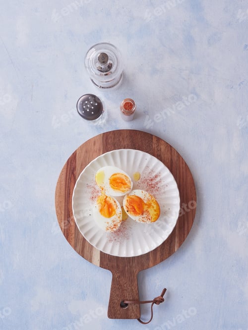 Preview: halves of hard-boiled eggs with olive oil and paprika. Salt and pepper shakers on the table.