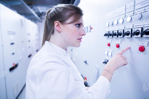 Preview: Young female scientist pointing at machine in technical room