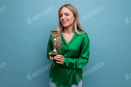 Preview: cute girl with championship cup on blue bright background with empty space