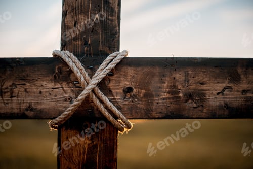 Preview: Closeup shot of a wooden cross with a rope wrapped around and a blurred background