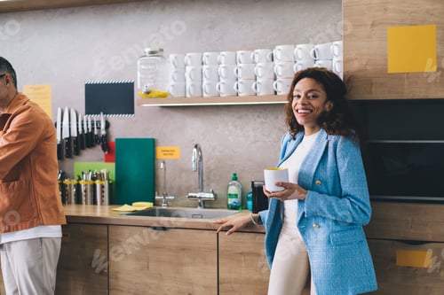 Preview: Smiling woman with cup of coffee in kitchen