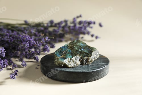 Preview: Aura. Beautiful labradorite and lavender flowers on beige background, closeup