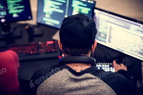 Preview: Rear view of tattooed man working on computer coding program