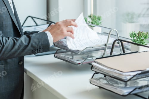 Preview: Cropped view of businessman looking for paper in document tray, while standing near window