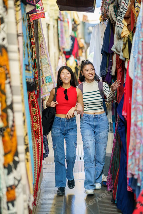 Preview: Female tourists shopping clothes in street bazaar