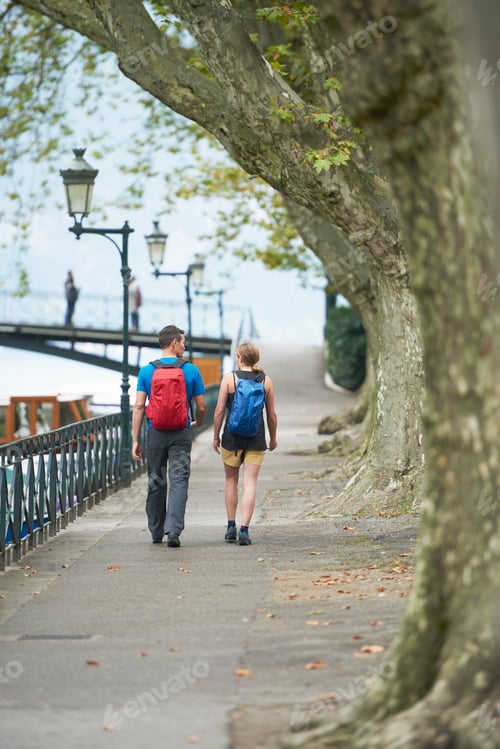 Preview: Mature man and young woman strolling along riverside, rear view, Annecy, Rhone-Alpes, France