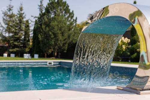 Preview: Modern outdoor swimming pool with a sleek water fountain feature, creating a refreshing
