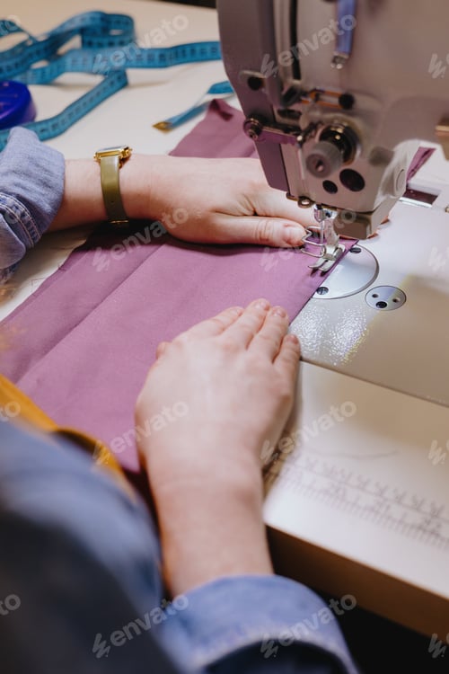 Preview: woman sews piece of cloth on sewing machine. industrial metal machine for all fabric tops.